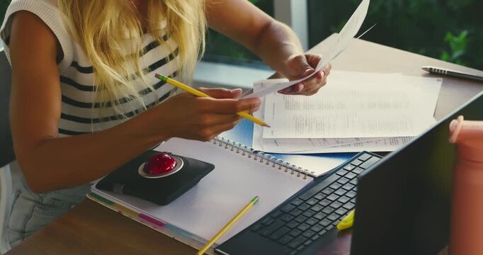 Woman Organizing Papers at Laptop in Home Office