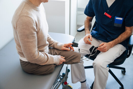 High angle view of male doctor using pulse oximeter on finger of amputee woman during medical exam in clinic