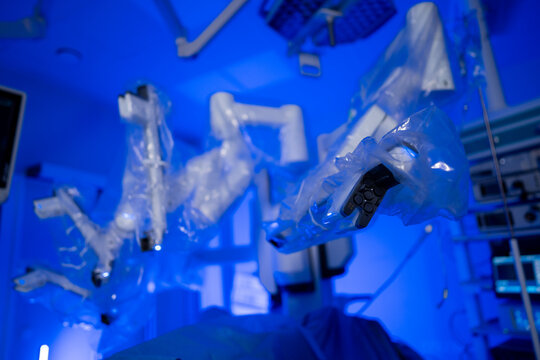 Robotic surgical arms in sterile protective covers in clinic. Medium shot of multiple robotic surgery manipulators wrapped in plastic film in high-tech operating room.