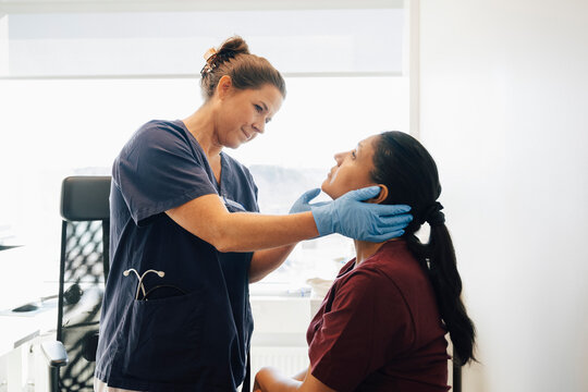 Female medical professional examining throat of woman in clinic