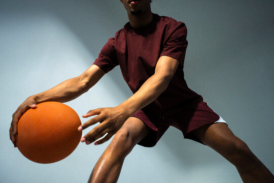 Low angle midsection view of male basketball player dribbling with ball against wall