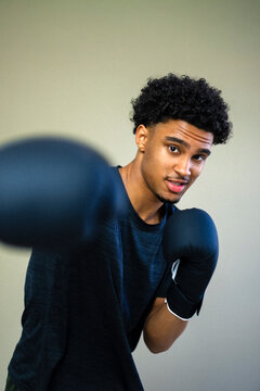 Portrait of young man practicing boxing against colored background