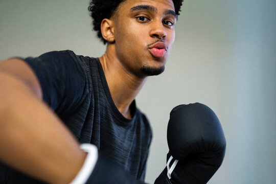 Young male athlete wearing black gloves during boxing training