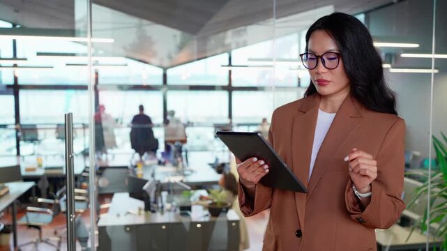 Executive CEO businesswoman professional holding digital tablet pc device for work in office workplace. Asian mature woman in suit and eyeglasses using pad computer for business planning. Copy space
