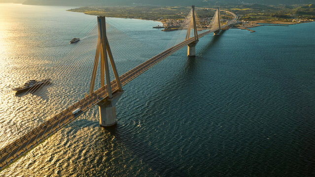 Rio-antirrio bridge spans the gulf of corinth in greece, its cable-stayed structure providing a vital road link, illuminated by the warm golden hour light reflecting on the water below
