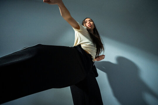 Low angle view of non-binary person doing contemporary dance near wall