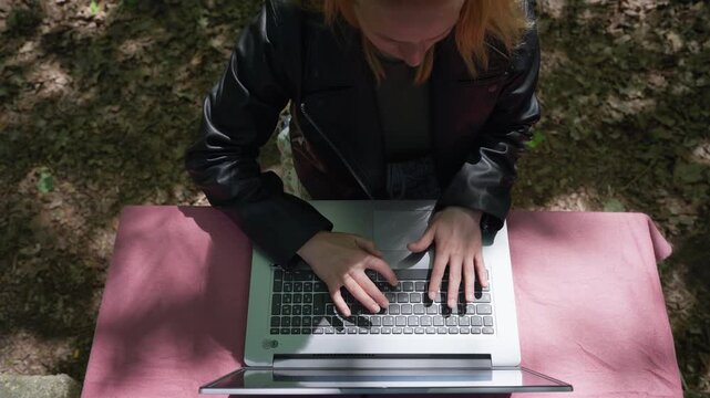 Top View of Female Freelancer Typing on Laptop in Nature: Concept of Creative Workspace, Remote Work, and Productivity Outdoors