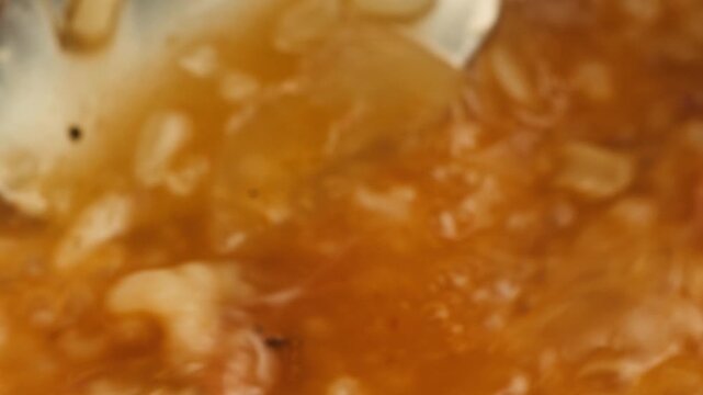 kharcho soup boiling and cooking close up, hot pot with greens rice and spoon spinning in a circle, georrgian restaurant, tomato soup macro. 