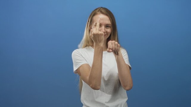 Woman shows middle finger with left hand and points index finger with right hand at camera in studio setting; defiance playful provocation.