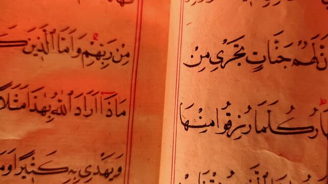 Static macro shot of an open ancient Quranic manuscript featuring bold Arabic script and red vocalization marks on aged parchment.