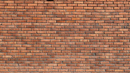 Fototapeta premium A detail of a red textured brick wall, rendered in bright sunlight, with old, weathered brickwork as a backdrop, and a crumbling brick facade or wall with rows of many bricks in the background.
