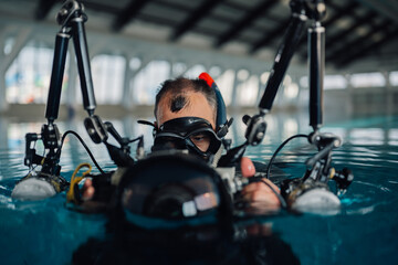 Naklejka premium Scuba diver holding underwater camera equipment in a swimming pool, preparing for practice and training