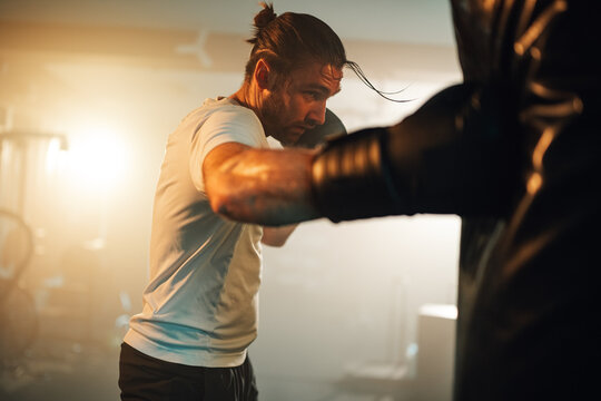 Man training boxing in a gym, hitting a punching bag. Showing strong effort, dedication, and active lifestyle