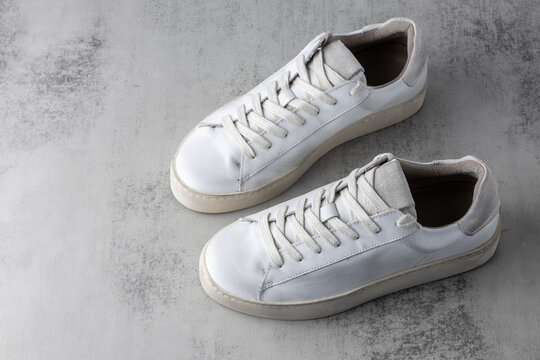 Trendy fashionable grey white leather in dirty grunge style women pair sneakers on neutral background. Casual style. Summer and spring shoes collection.