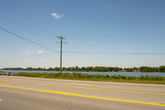 A roadside view of Lake Chicot with a utility pole and power lines in eastern Arkansas on a sunny spring day