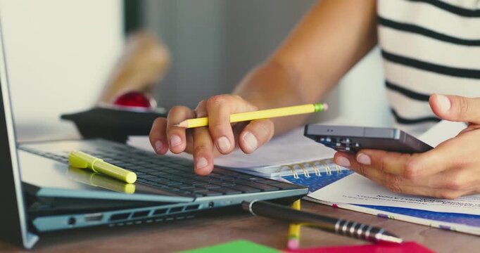 Person Using Laptop and Calculator at Desk