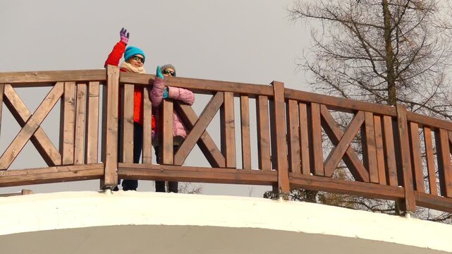 Two little beautiful girls walk on bridge near Strbske Pleso, is a favorite ski, tourist, and health resort in the High Tatras, Slovakia.