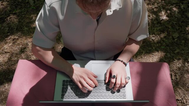 Digital Nomad Working on Laptop in Nature: Top View of a Freelancer Working Remotely Outdoors in a Forest Setting