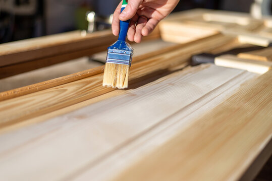 Applying wood varnish with brush on new wooden doors