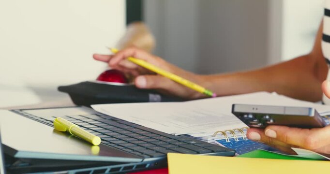 Person Using Calculator and Taking Notes at Desk