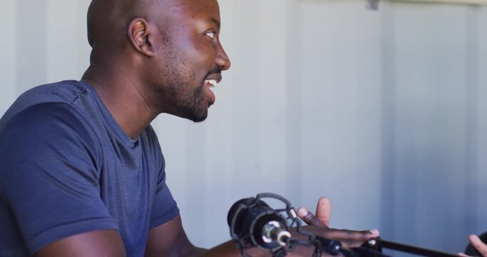 African American cohosts in studio, man leaning to mic asking question, woman answering with tablet