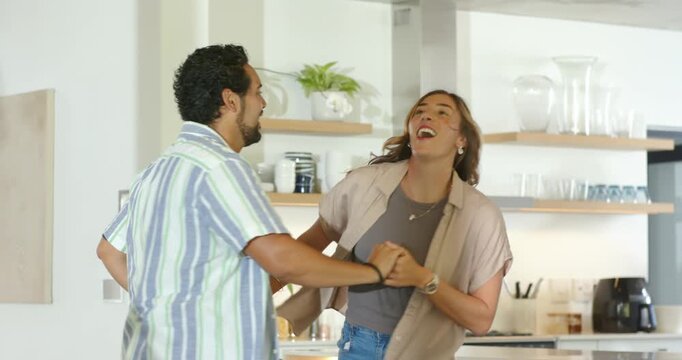 Couple, man pulling woman's hand, spinning and lifting into dip, celebrating closeness in kitchen