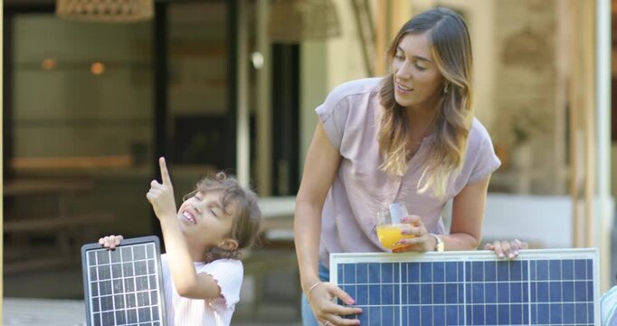 Family child on patio, sun guiding girl pointing panel, parents holding panel showing solar power