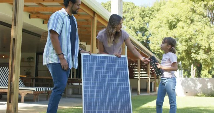 Diverse family checking panels youth lifting mini panel urging parents holding large panel on lawn