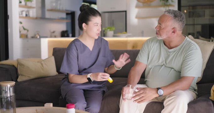 Asian caregiver in scrubs holding yellow pill bottle, explaining dosage while man reading label