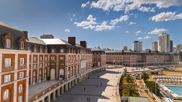 Mar del Plata, Argentina - December 12, 2025: Aerial drone view of historic Casino complex with red brick and stone facade, paved plaza, swimming pool area and city skyline with residential towers