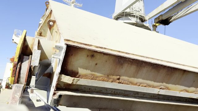 opening ocean going ship hatch covers of cargo holds. huge rollers rotate and lift massive covers. wheat loaded, grain dust. ship construction.