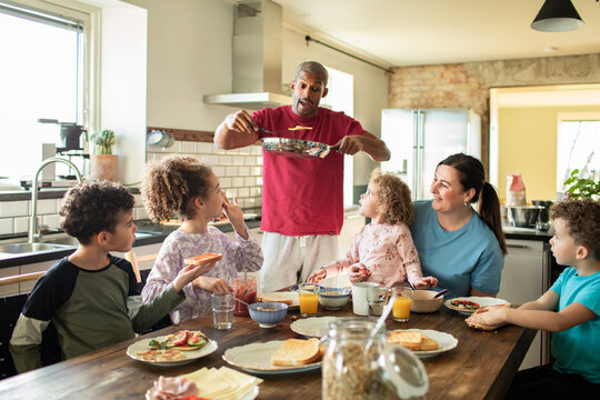 Parents and children having breakfast together at home in the kitchen