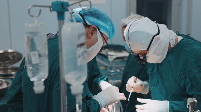 Surgeons performing surgery operation in hospital operating room with IV drips in foreground, medical specialists working during complex surgical procedure under sterile conditions