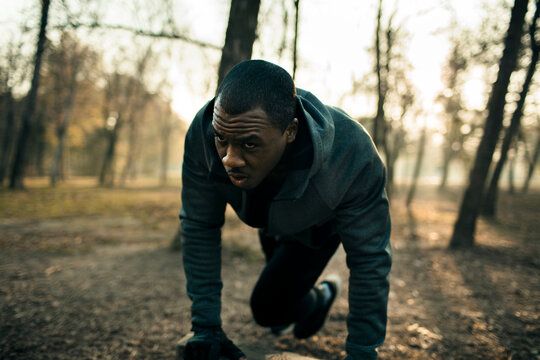 Focused male athlete training on forest trail at sunrise