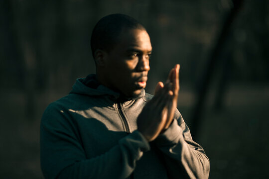 Athletic man warming up hands outdoors in park