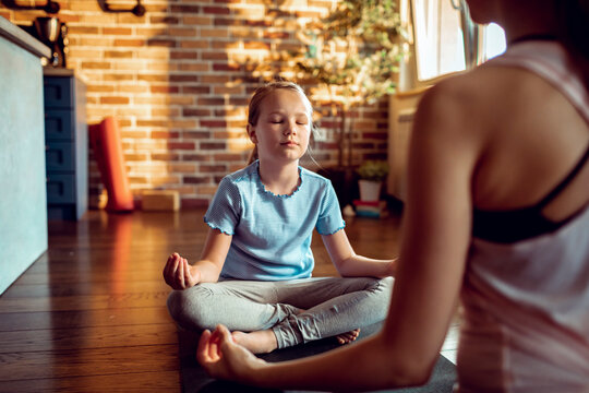 Young girl meditating with parent at home