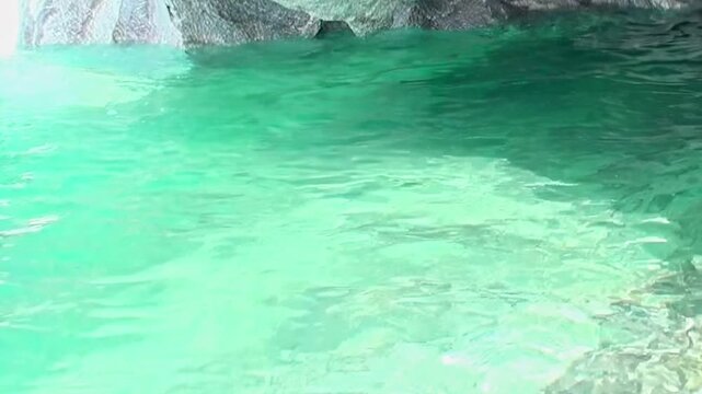 Experience the ethereal beauty of Patagonia's Marble Caves. Luminous turquoise waters gently ripple, revealing nature's intricate artistry within these ancient geological formations on a bright day.