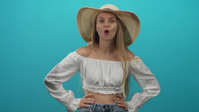 Woman wearing a straw sunhat with bare midriff, hands on hips and pouting lips in studio; playful sass surprise.