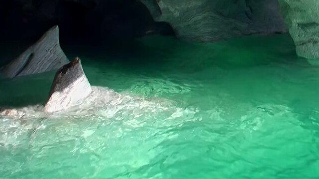 Serene emerald water gently laps against the smooth, sculpted walls of Patagonia's Marble Caves. Discover this breathtaking geological marvel, a natural artwork shimmering with light.