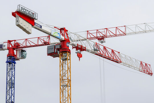Nancy, France - April 12th 2022 : View on a flat-top tower crane Potain MDT 219 J10 with another Potain tower crane behind on a construction site for the construction of a building.	