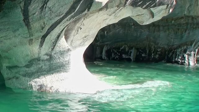 Experience the serene beauty of Patagonia's Marble Caves. Sunlight dances on crystalline turquoise water, illuminating intricate, sculpted marble formations inside this natural sanctuary.