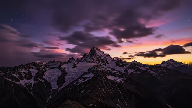 Snow mountain peak at sunset with dramatic purple sky and glowing clouds over rugged alpine ridge scenic landscape nature view