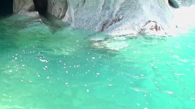 Marvel at Patagonia's exquisite Marble Caves. Turquoise waters sparkle against ancient, naturally carved rock. A serene and majestic display of Earth's artistic power unfolds in bright daytime light.