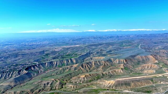 Aerial view of rolling hills with green patches and winding roads