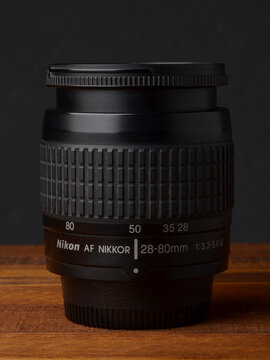 PERPIGNAN, FRANCE - MAY 6, 2026: A Nikon Nikkor 28-80mm f3.3-5.6 G zoom lens on a wooden surface. A compact and lightweight photographic lens for digital and film SLR cameras