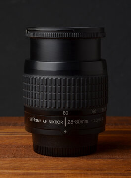 PERPIGNAN, FRANCE - MAY 6, 2026: A Nikon Nikkor 28-80mm f3.3-5.6 G zoom lens on a wooden surface. A compact and lightweight photographic lens for digital and film SLR cameras