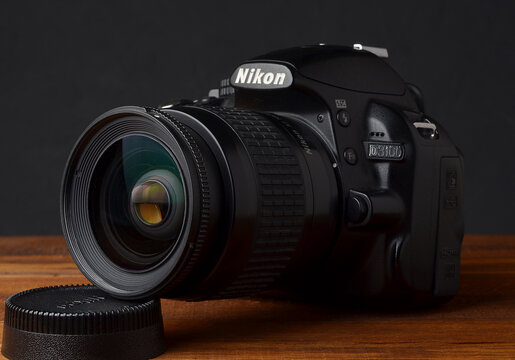 PERPIGNAN, FRANCE - MAY 6, 2026: A Nikon D3100 DSLR camera with a Nikkor 28-80mm f3.3-5.6 G lens on a wooden tabletop. An affordable photography setup for students and hobbyists, captured in a studio 