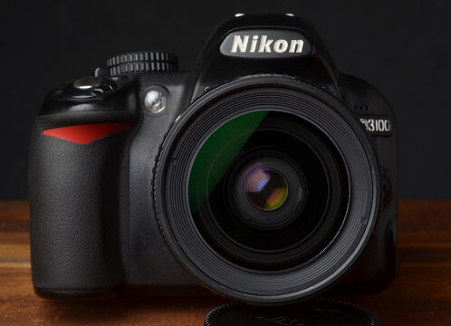 PERPIGNAN, FRANCE - MAY 6, 2026: A Nikon D3100 DSLR camera with a Nikkor 28-80mm f3.3-5.6 G lens on a wooden tabletop. An affordable photography setup for students and hobbyists, captured in a studio 