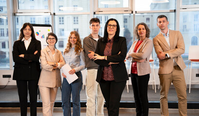 A confident business team stands together in a modern office. Corporate professionals, teamwork, leadership, success, and business center confidence define the group portrait. © Martinesku