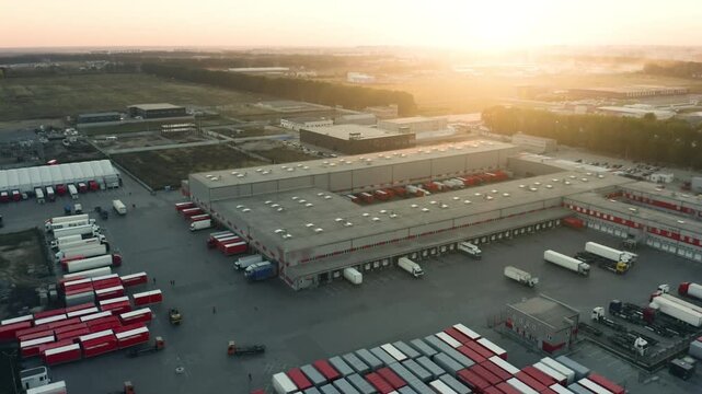 Large Logistics Park and Sorting Complex Aerial Drone View at Golden Hour | Hundreds of Red White Trailers at Loading Docks | Freight Distribution Hub and Supply Chain Concept